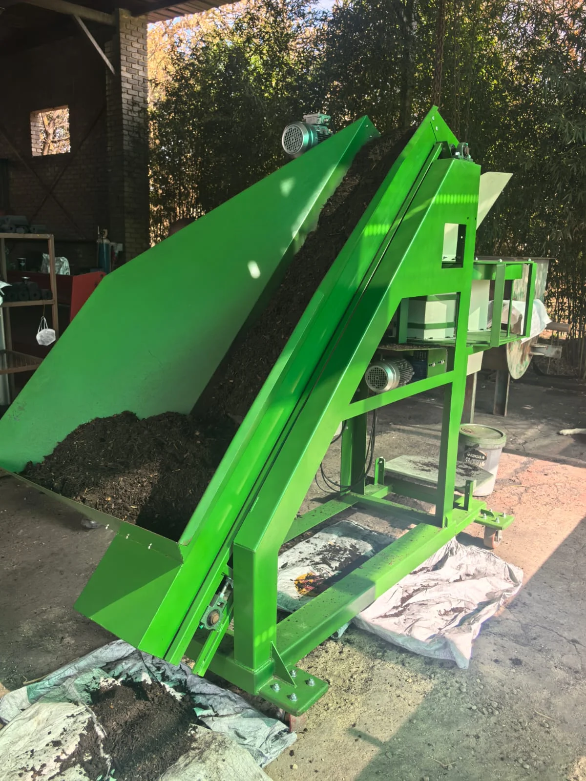 Inclined feed conveyor loading bulk material into the gravity packer